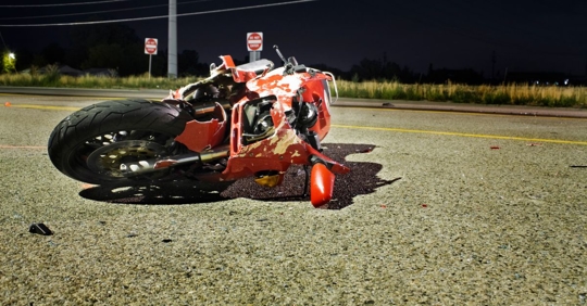 damaged motorcycle with chipped paint laying on the road