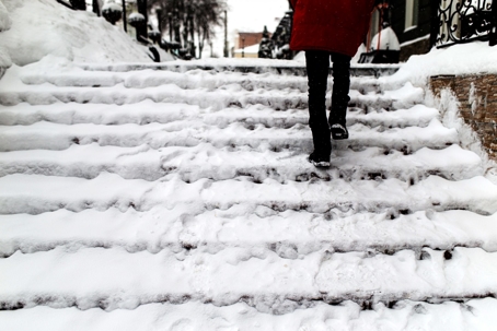 A woman walking up a snow covered stairs