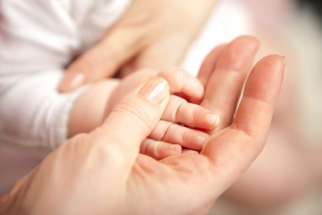 A mother holding her baby's hand