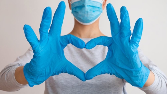 Nurse in mask making heart with hands