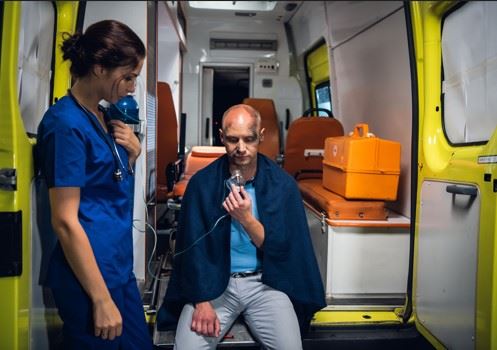 injured man sitting in back of ambulance with oxygen mask